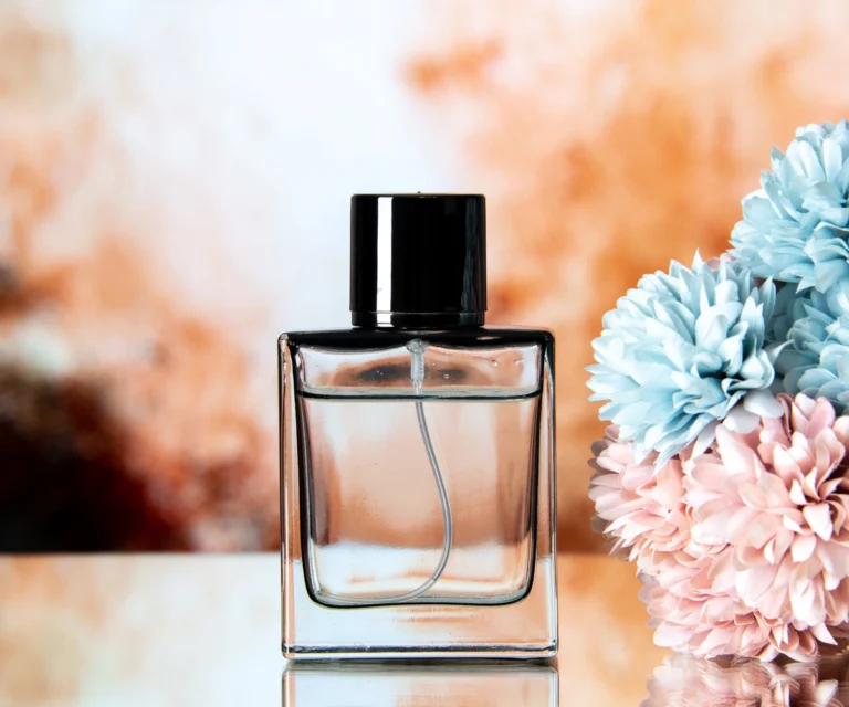Front view elegant women perfume colored flowers beige abstract background as an example of maklon parfum.